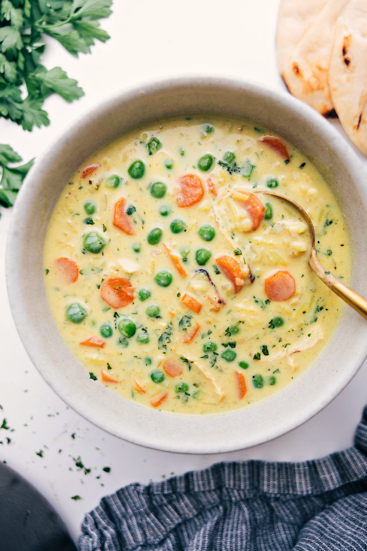 Chicken Curry Rice Soup is out of this world good! We've got tender shredded chicken, rice, carrots, onion, and celery all simmering together in a rich, creamy, and flavorful base that will have you coming back for seconds (or thirds). Get ready to cozy up with a big bowl of this comforting goodness! Recipe via chelseasmessyapron #dinner #quick #easy #simple #best #familyfriendly #comfortfood #healthy #curry #chicken #rice #soup Chicken Curry Rice Soup served in a bowl with a spoon, ready to enjoy.