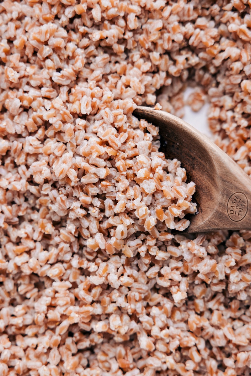 Pan of cooked farro being scooped with a wooden spoon.