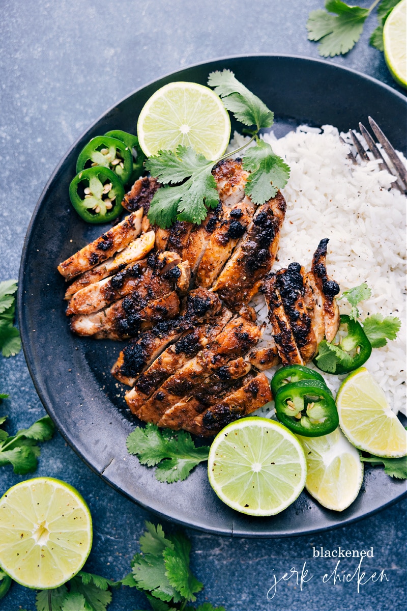 Overhead view of Jerk Chicken served with rice, jalapenos and lime