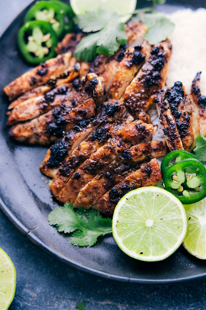 Jerk Chicken on a plate with lime slices and jalapenos