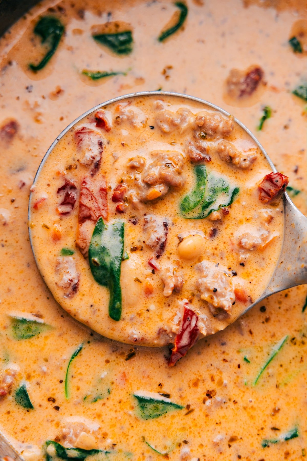 The best Tuscan soup in a pot, scooped up with a ladle, showing all the delicious ingredients.