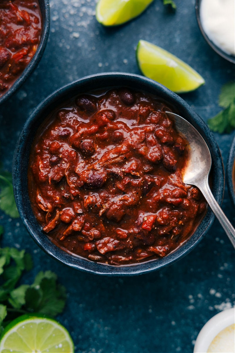 Our favorite Chili Con Carne recipe! This chili dish features succulent pieces of beef slow-cooked in a medley of crushed tomatoes, diced onions, and peppers. A tantalizing blend of chili spices and a touch of heat create a warm and comforting meal that's sure to satisfy. Serve it up with your favorite toppings and dive into a delicious bowl of the best chili ever! Recipe via chelseasmessyapron #dinner #quick #easy #simple #familyfriendly #kidfriendly #mexican #chili #concarne Overhead image of the Chile Con Carne ready to be enjoyed