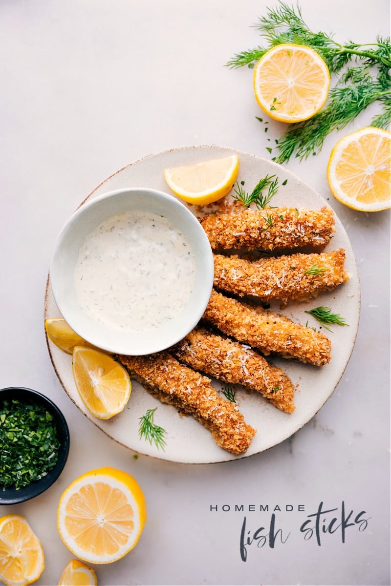 Get ready to indulge in a sophisticated take on a childhood favorite with this recipe for homemade Fish Sticks! Made with fresh cod, a blend of savory spices, and coated in crispy Panko breadcrumbs, these fish sticks are not only delicious, but also a healthier and more upscale alternative to the frozen, boxed versions. Recipe via chelseasmessyapron #dinner #quick #easy #simple #familyfriendly #comfortfood #homemade #fishsticks Overhead image of the homemade fish sticks