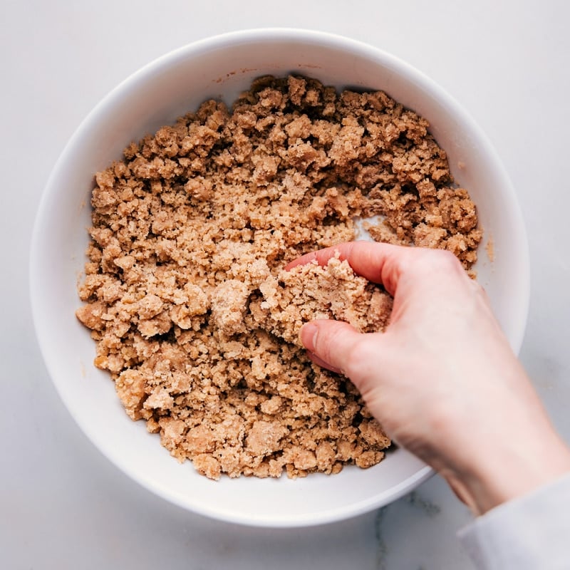 Process shots of how to make streusel-- image of a hand mixing together the streusel