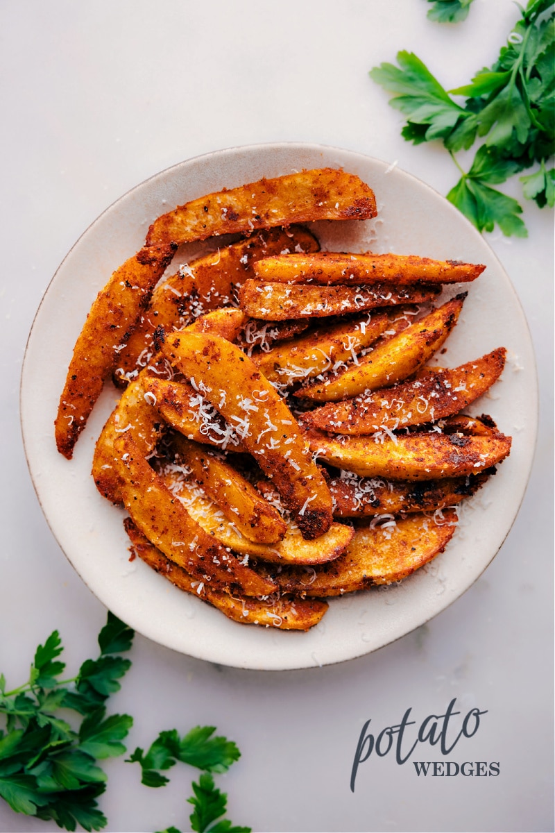 Looking for a healthier alternative to french fries that doesn't skimp on flavor and texture? Look no further than these crispy, fluffy baked Potato Wedges! These potatoes are the epitome of perfection, with a crisp exterior and soft, pillowy interior that is completely irresistible. Best of all, they're a budget-friendly and filling side dish that can be paired with just about anything. So skip the deep fryer and whip up a batch of these potatoes for your next meal! Recipe via chelseasmessyapron #sidedish #best #quick #easy #simple #comfortfood #fries #potato #wedges Overhead image of Potato Wedges