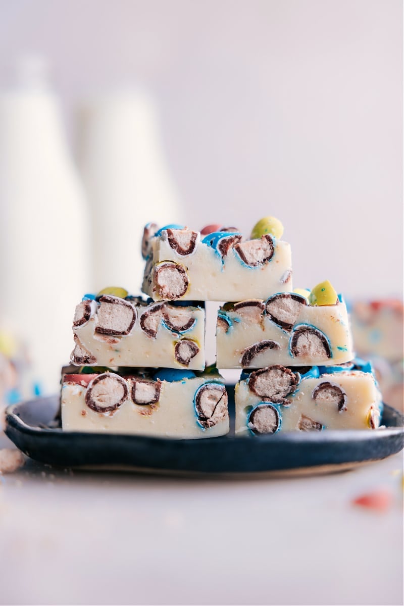 This mouth-watering Robin Egg Fudge recipe is pure indulgence! The velvety white chocolate pairs perfectly with the nutty and sweet flavor of robin egg candies. The added crunch of the candy pieces creates a delightful texture that will keep you coming back for more. This recipe is super easy to make and doesn't require any special candy-making equipment! No need for a candy thermometer or any fancy gadgets, making it the perfect recipe for both novice and experienced bakers alike. Recipe via chelseasmessyapron #dessert #best #quick #easy #simple #treat #nobake #festive #robinegg #fudge Image of Robin Egg Eudge stacked on a plate