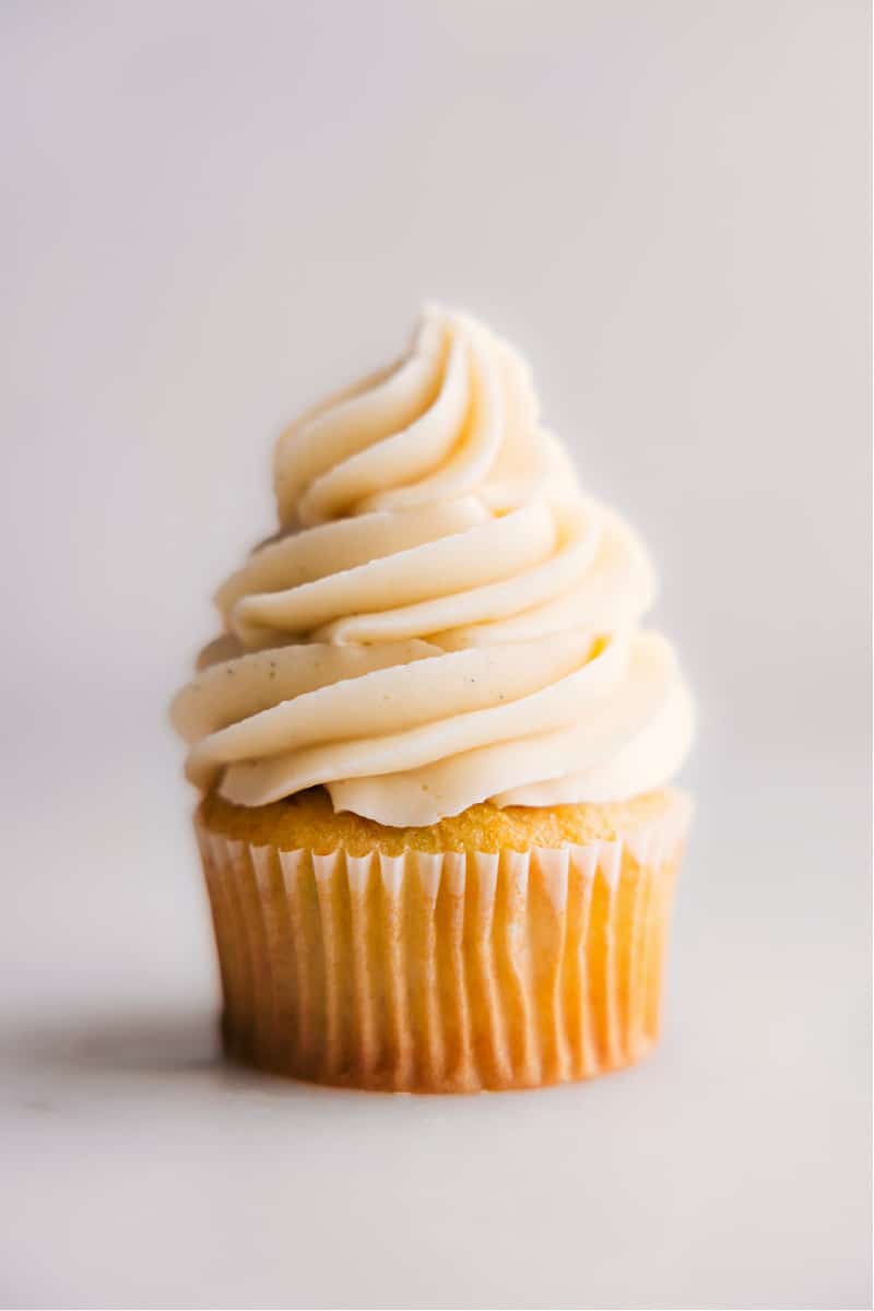 This Vanilla Frosting Recipe is a great, versatile recipe that can be used for all kinds of desserts from cakes and cupcakes to cookies and more. It pairs well with various flavors, such as chocolate, lemon, and strawberry, making it a great all-purpose frosting. Recipe via chelseasmessyapron #dessert #best #quick #easy #simple #familyfriendly #treat #dip #cupcake #cake #vanilla #frosting #vanillafrosting Image of a cupcake topped with Vanilla Frosting