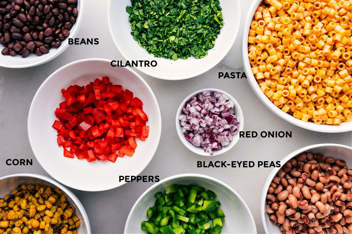 All the ingredients for this recipe are prepped and ready for easy assembly, including beans, cilantro, pasta, onions, and peppers.