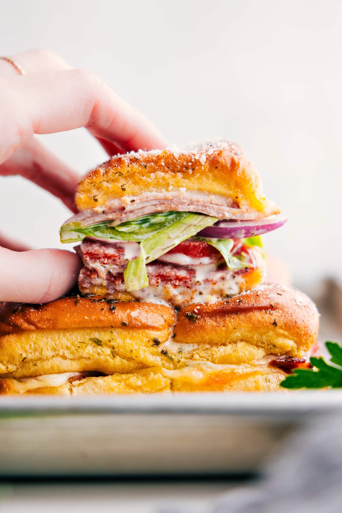 These Grinder Sliders offer bold and robust flavors from the savory combination of salami, pepperoni, and ham complemented by the rich and creamy melted Provolone cheese, all nestled within sweet Hawaiian rolls. The sliders are topped with a fresh and tangy sub slaw, featuring crisp iceberg lettuce, zingy banana peppers, and a sharp, bright dressing, offering a burst of flavors in every bite. Recipe via chelseasmessyapron #lunch #quick #easy #simple #familyfriendly #kidfriendly #comfortfood #turkey #pepperoni #grinder #sliders