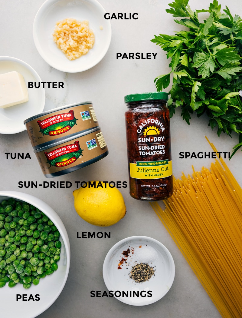 Various ingredients for creating the dish, including noodles, peas, sun-dried tomatoes, lemon, and other essential elements, laid out in preparation for cooking.