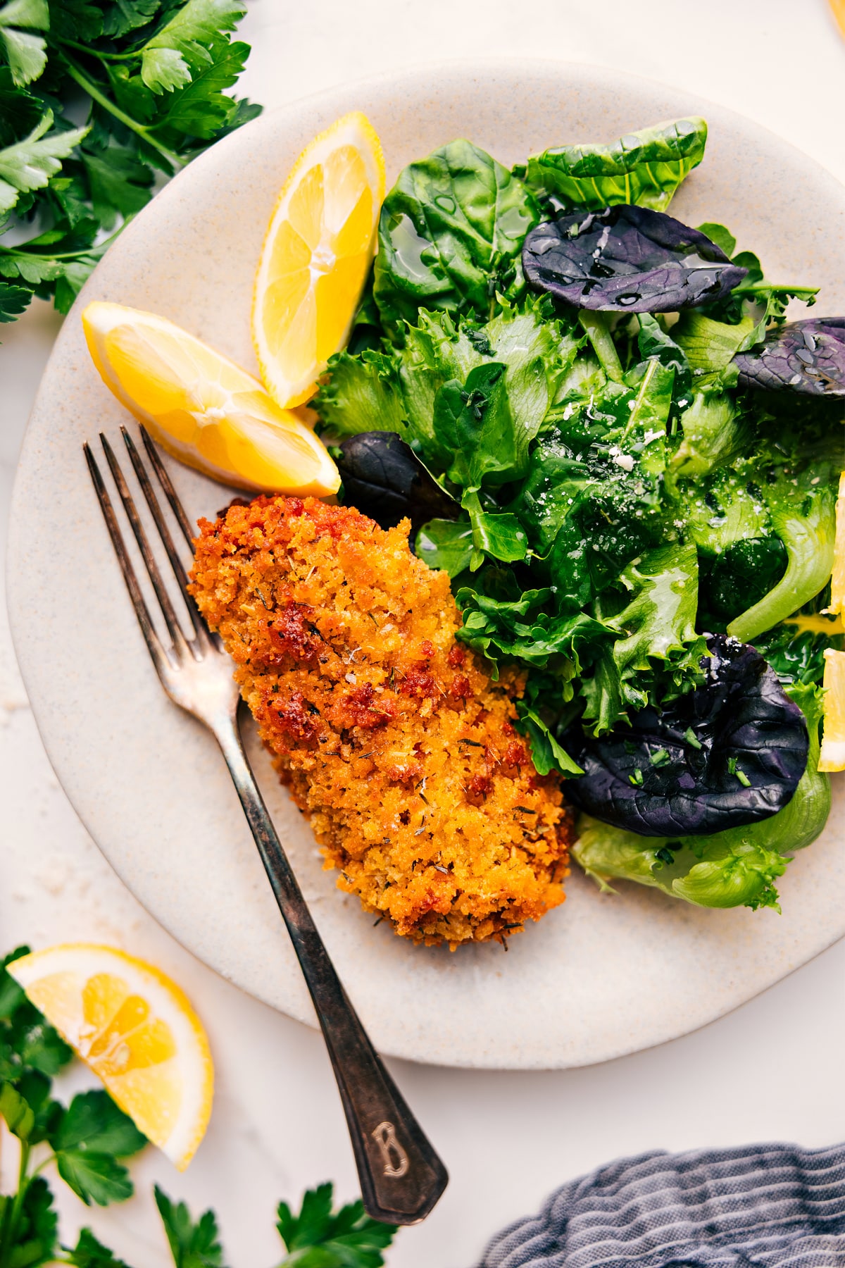 Baked cod recipe served on a plate with a bed of lettuce on the side.