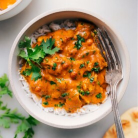 Bowl of creamy instant pot butter chicken served over rice, garnished with fresh cilantro.