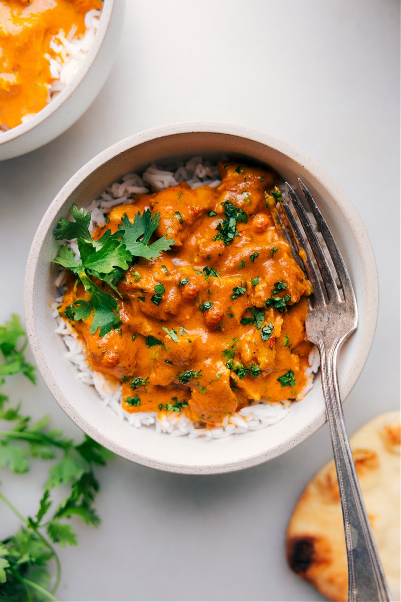 Bowl of creamy instant pot butter chicken served over rice, garnished with fresh cilantro.