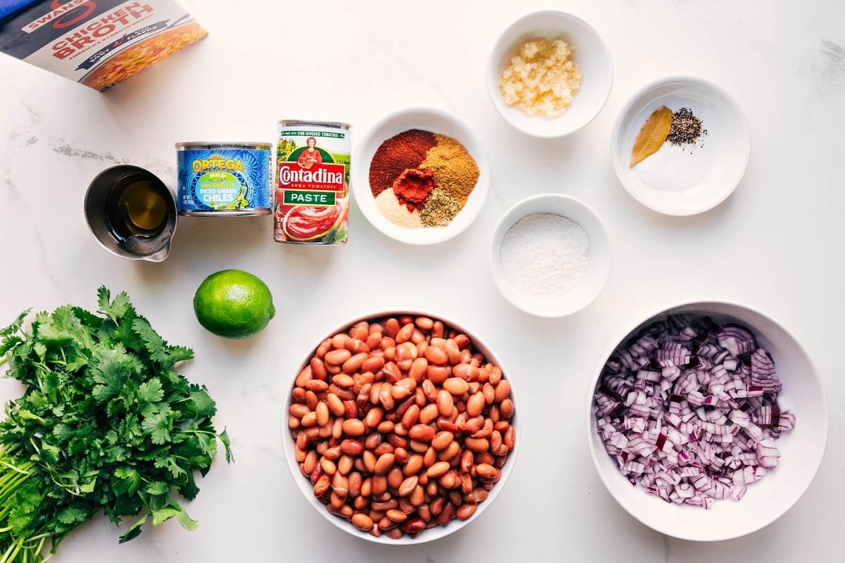 All the ingredients in this recipe prepped out for easy assembly including the broth, cilantro, lime, oil, beans, onion, seasonings, garlic, green chiles, and flour.