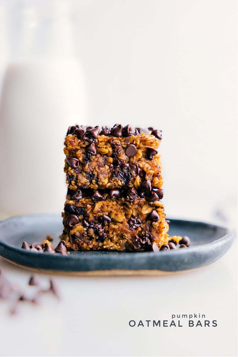 Pumpkin Oatmeal Bars are a taste of fall, blending the warmth of hearty oats and creamy pumpkin, with bursts of chocolate in every bite. They strike the perfect balance for a wholesome snack or a great on-the-go breakfast treat. Recipe via ChelseasMessyApron.com #pumpkin #pumpkinspice #oats #bars #breakfast #snack #chocolate #cinnamon Two Pumpkin Oatmeal Bars on a plate