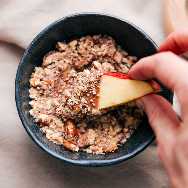 Overhead image of an apple slice being dipped in a topping