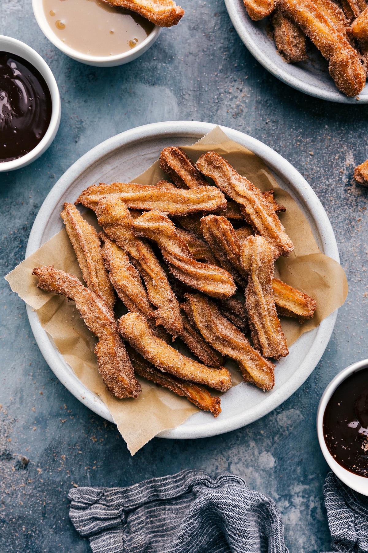 Plate of churros served with a side bowl of rich chocolate sauce.