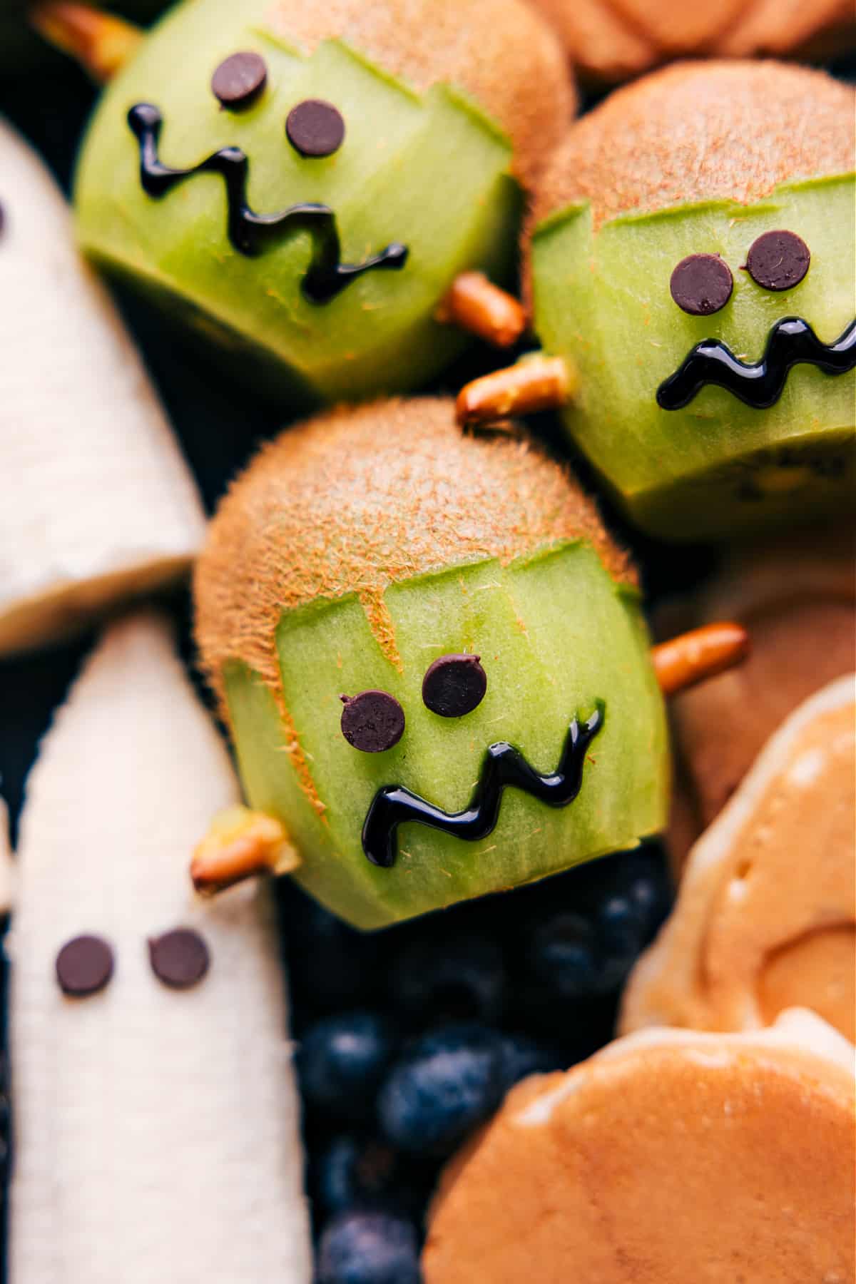 Kiwi carved and decorated to resemble Frankenstein's face for a Halloween treat.