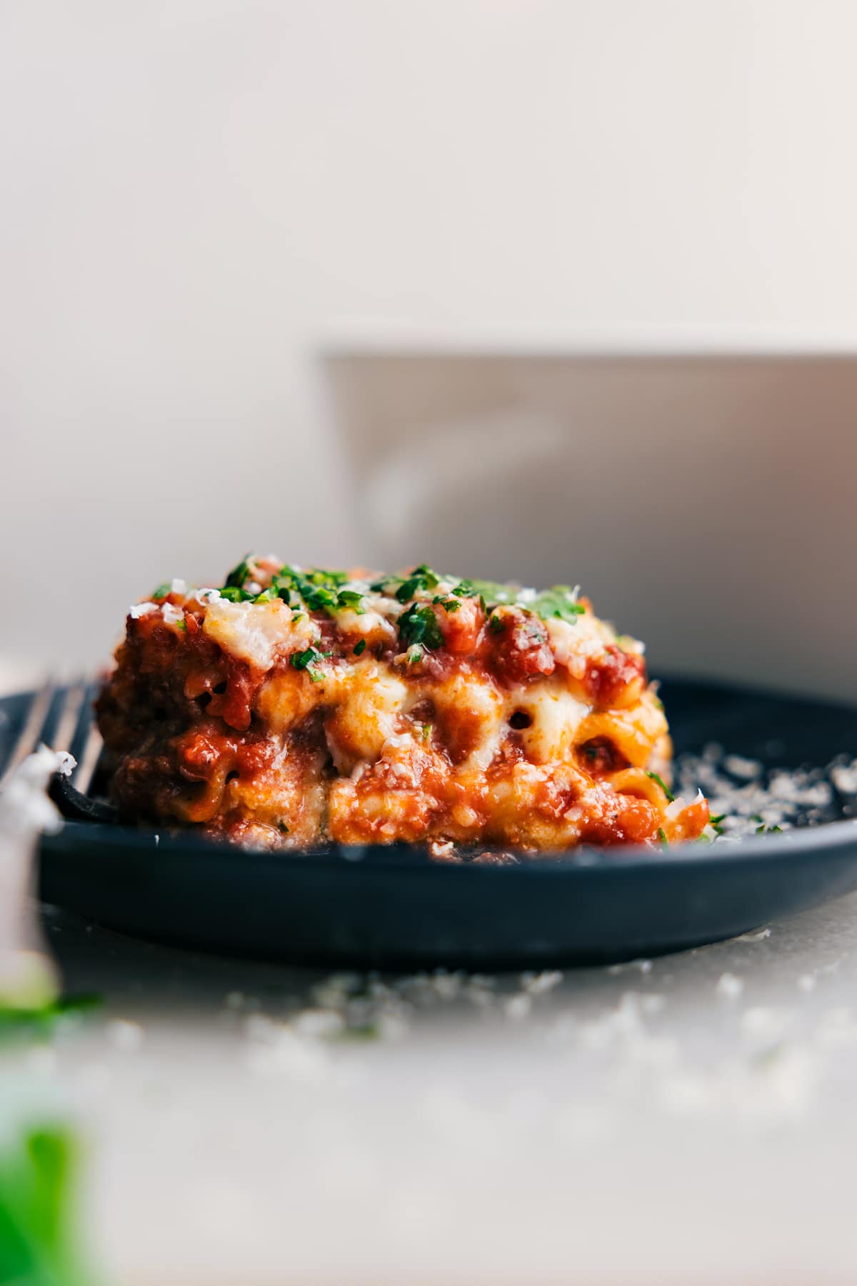 Steaming slice of Lasagna layered with cheese and sauce on a plate, ready to eat.