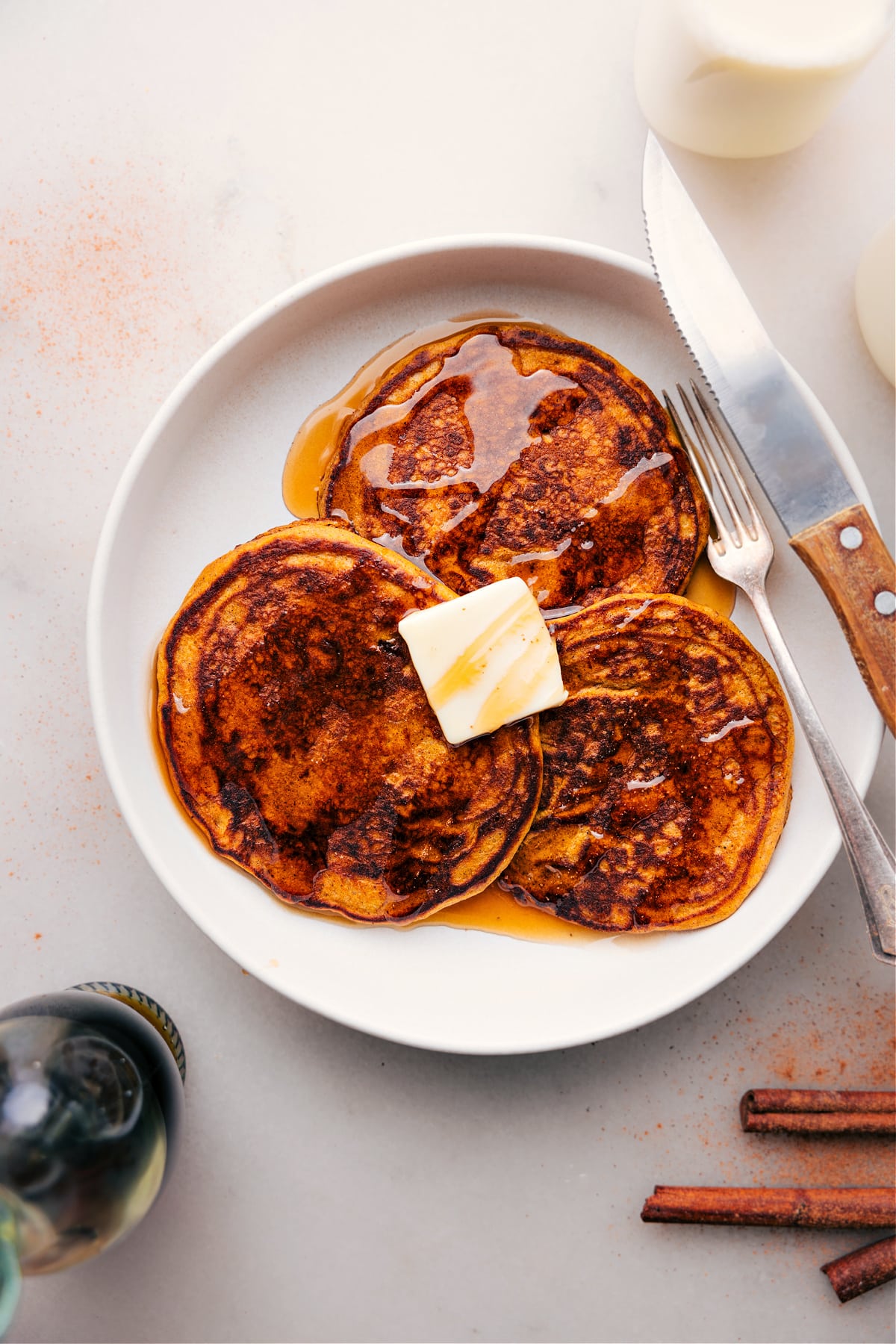 Plate of Three Pumpkin Pancakes drizzled with maple syrup.