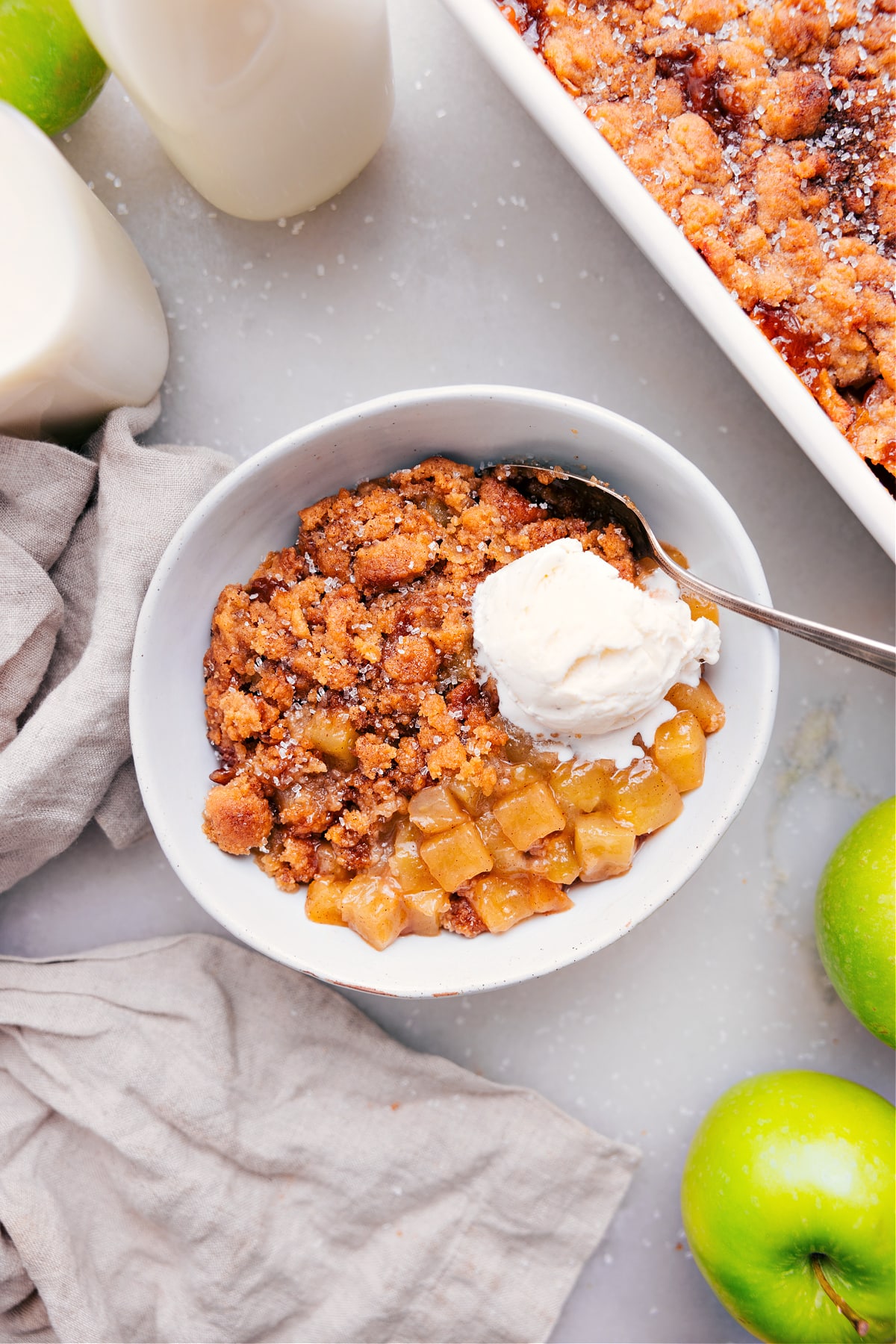 Apple cobbler with a scoop of ice cream in a bowl with a spoon.