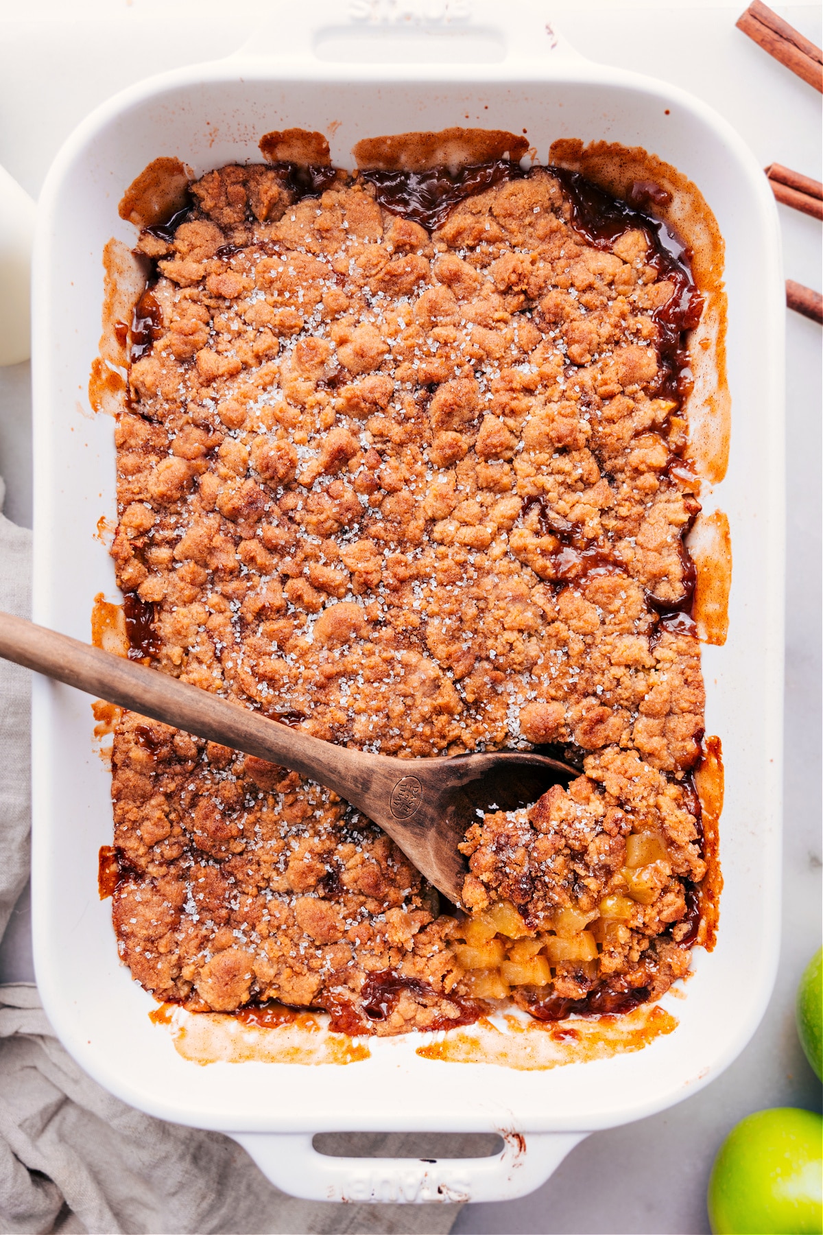 Freshly baked apple crumble pie with a spoonful taken out and a spoon in it.