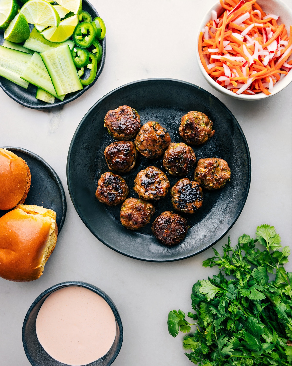 Perfectly baked pork banh mi meatballs presented amid an array of fresh ingredients, poised for slider assembly.