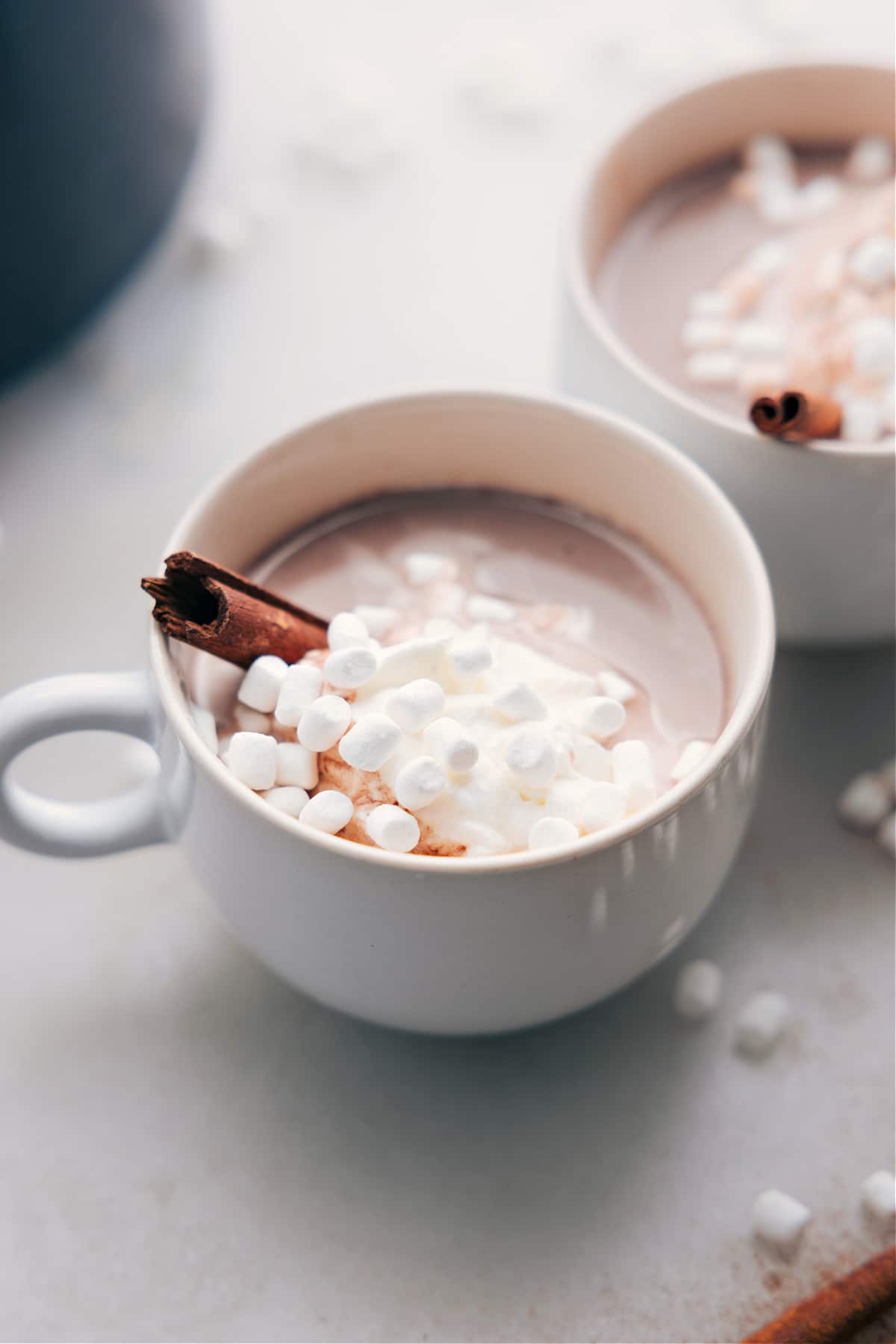 Finished steaming beverage in a mug, lavishly topped with whipped cream, marshmallows, and a cinnamon stick.
