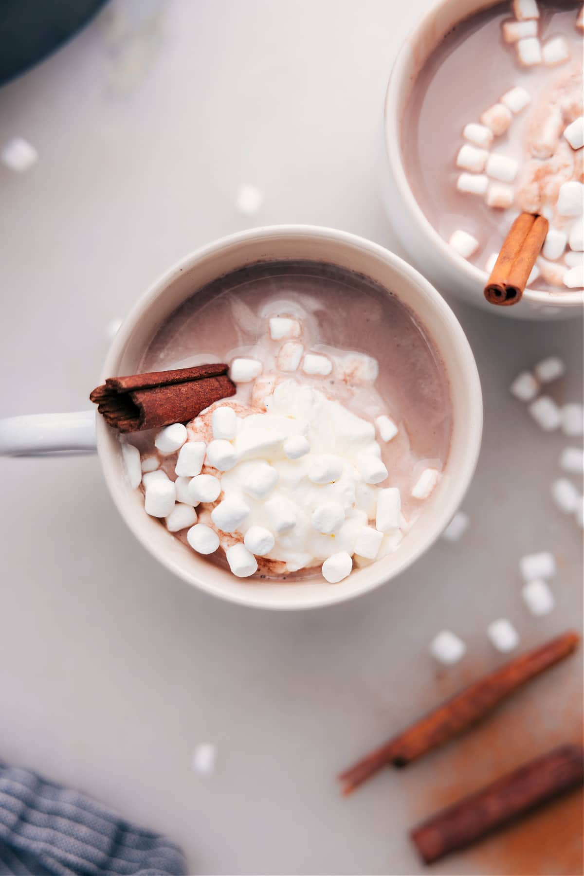 Steaming Mexican hot chocolate crowned with fluffy whipped cream, marshmallows, and a cinnamon stick for the final touch.