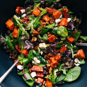 A vibrant bowl of sweet potato salad, featuring diced roasted sweet potatoes mixed with various colorful ingredients.