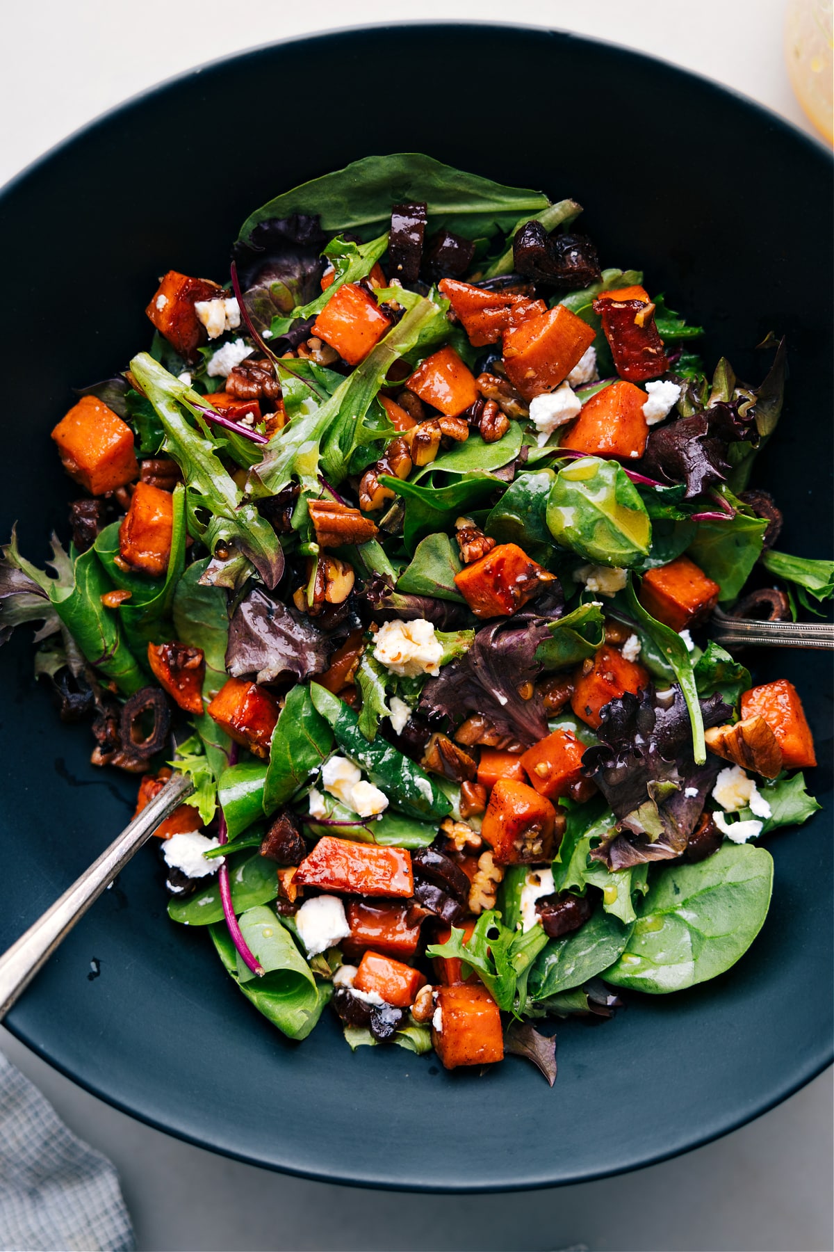 A vibrant bowl of sweet potato salad, featuring diced roasted sweet potatoes mixed with various colorful ingredients.