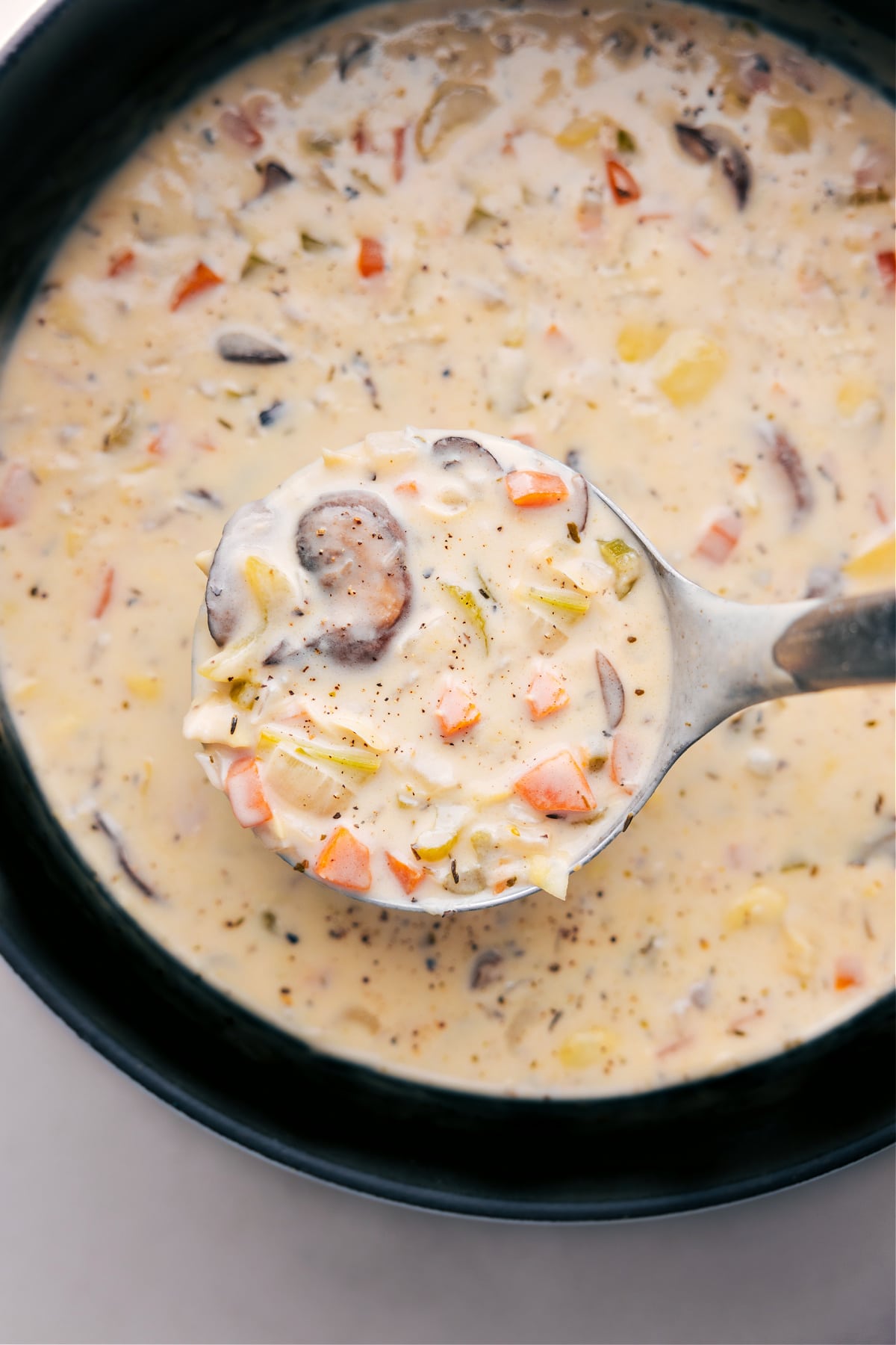 Creamy and rich artichoke soup, with a wooden ladle scooping out a steaming serving ready to be enjoyed.