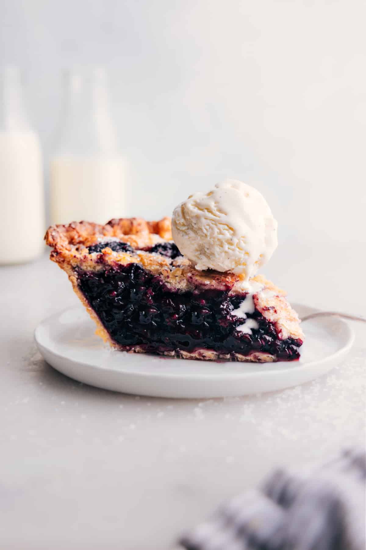 Slice of berry pie with ice cream on top.