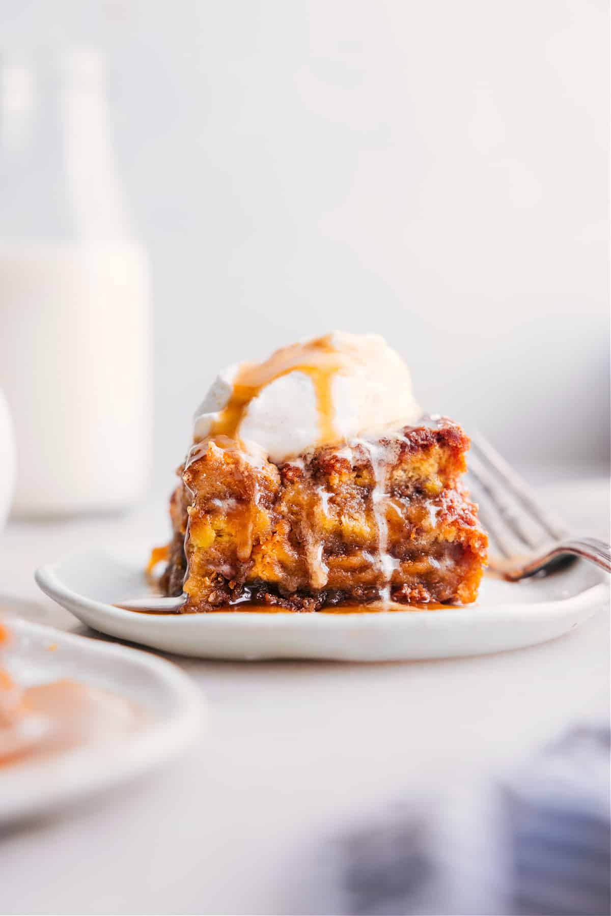 A slice of bread pudding topped with a scoop of ice cream, served warm as a delicious dessert.