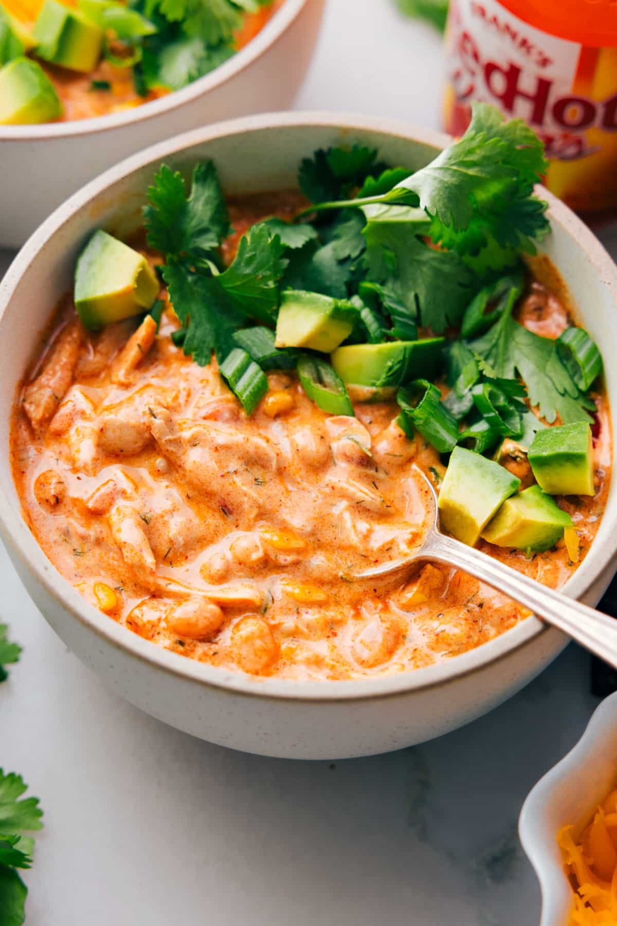 A big bowl of Buffalo Chicken Chili with a spoon in it.