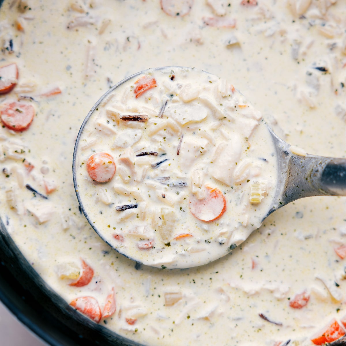 Big ladle full of Creamy Chicken and Wild Rce Soup being taken out of the pot.