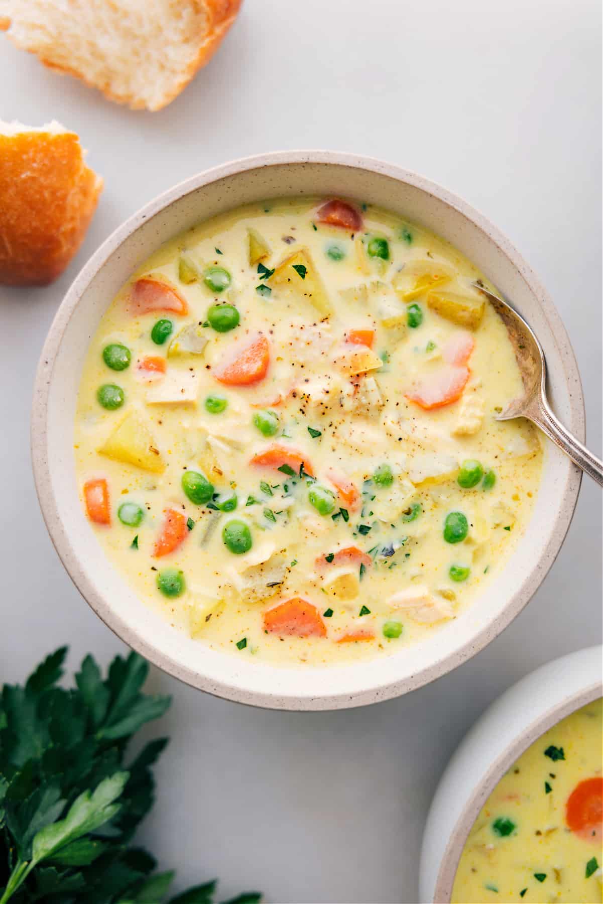 A bowl filled with the finished hearty Curry Chicken Chowder, topped with fresh herbs, and served alongside bread for a delicious and satisfying meal.