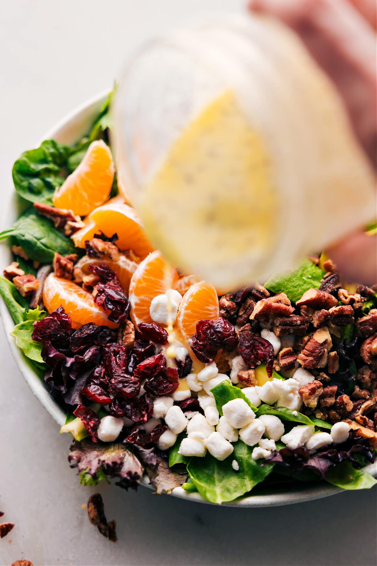 Lemon poppy seed dressing being poured over the salad.