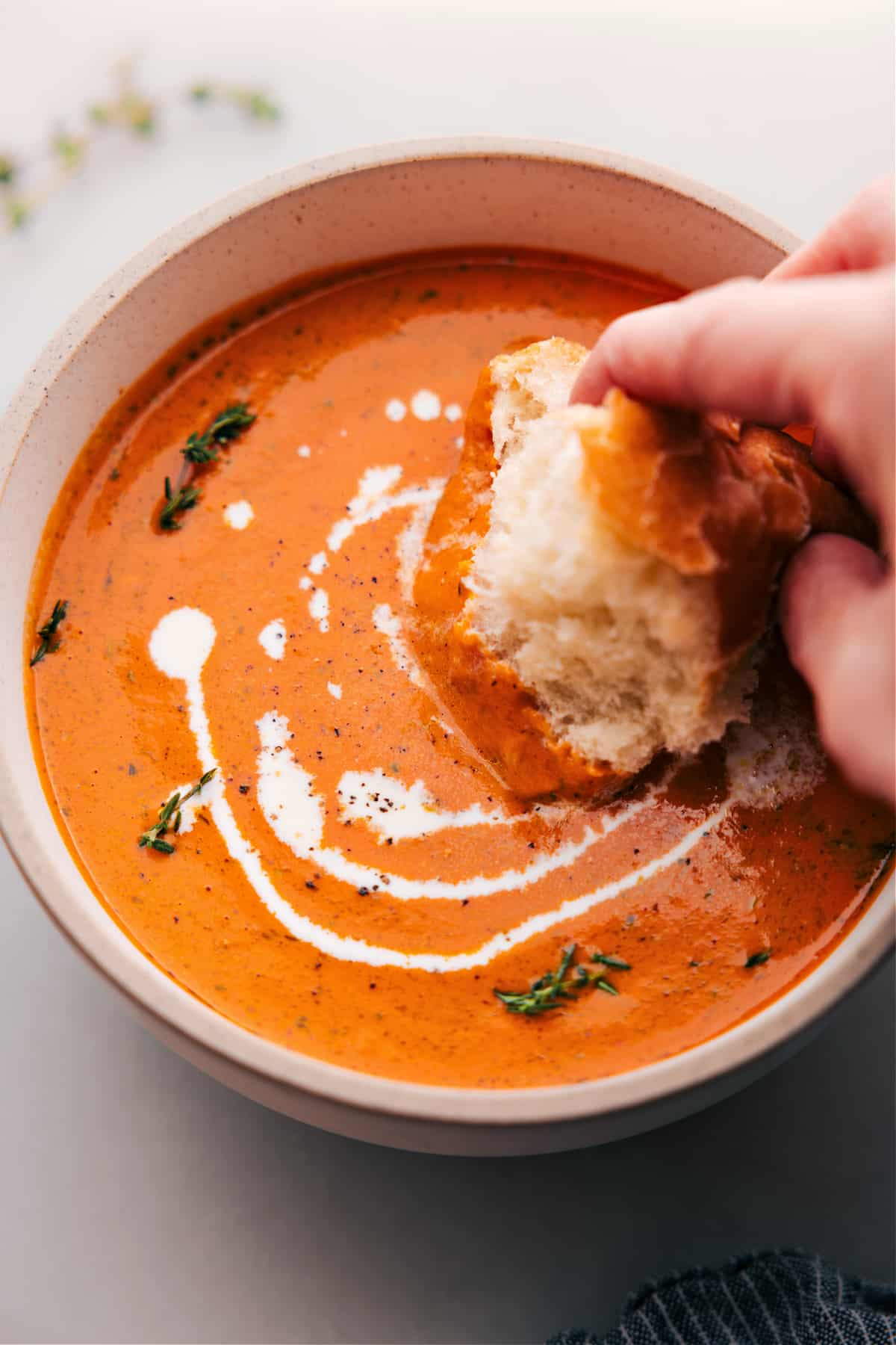 Big bowl of Roasted Red Pepper Soup being dipped with bread.