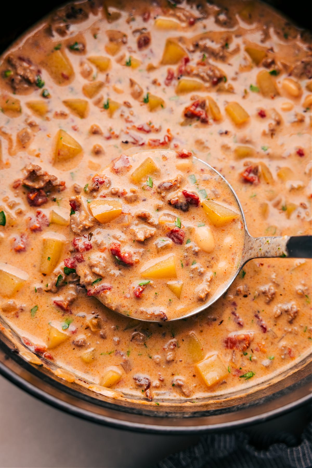 A pan filled with the finished tuscan sausage & potato soup, full of flavor and ingredients, warm and ready to be enjoyed as a delicious meal.