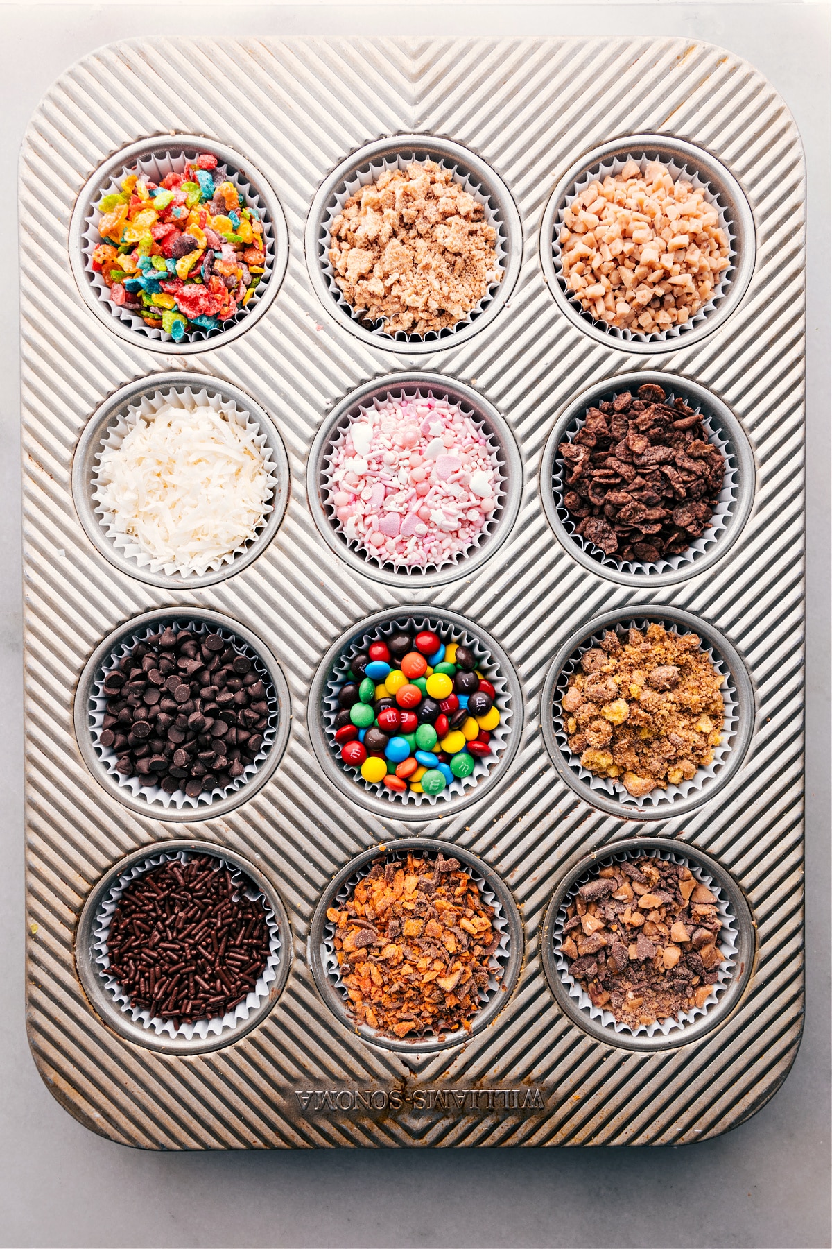 Image of a muffin pan with all the ingredients used to dip the strawberries for Chocolate-Covered Strawberry Dessert Bar in the various wells.