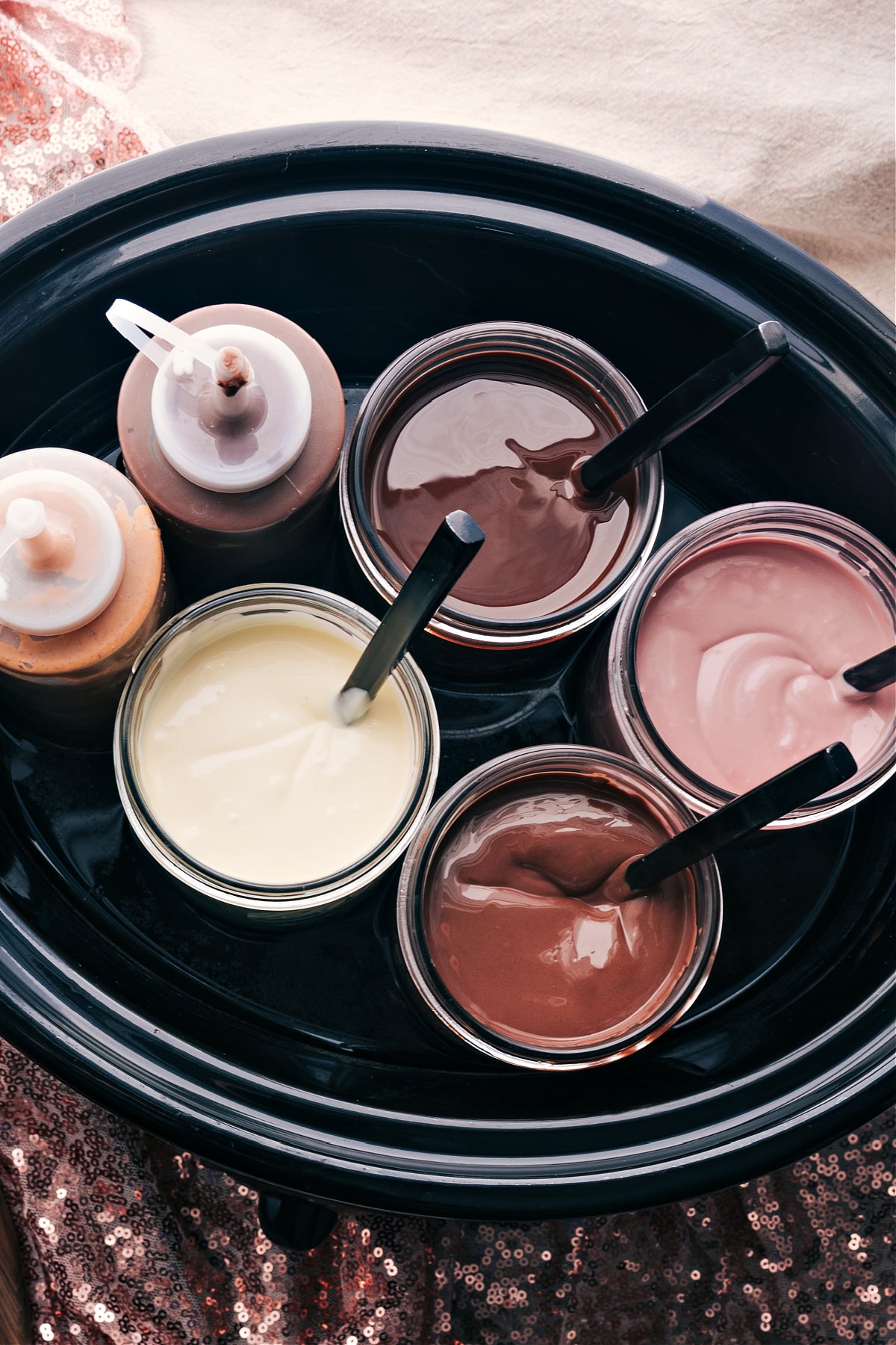 A slow cooker filled with warm water to keep the bottles of chocolate warm and gooey