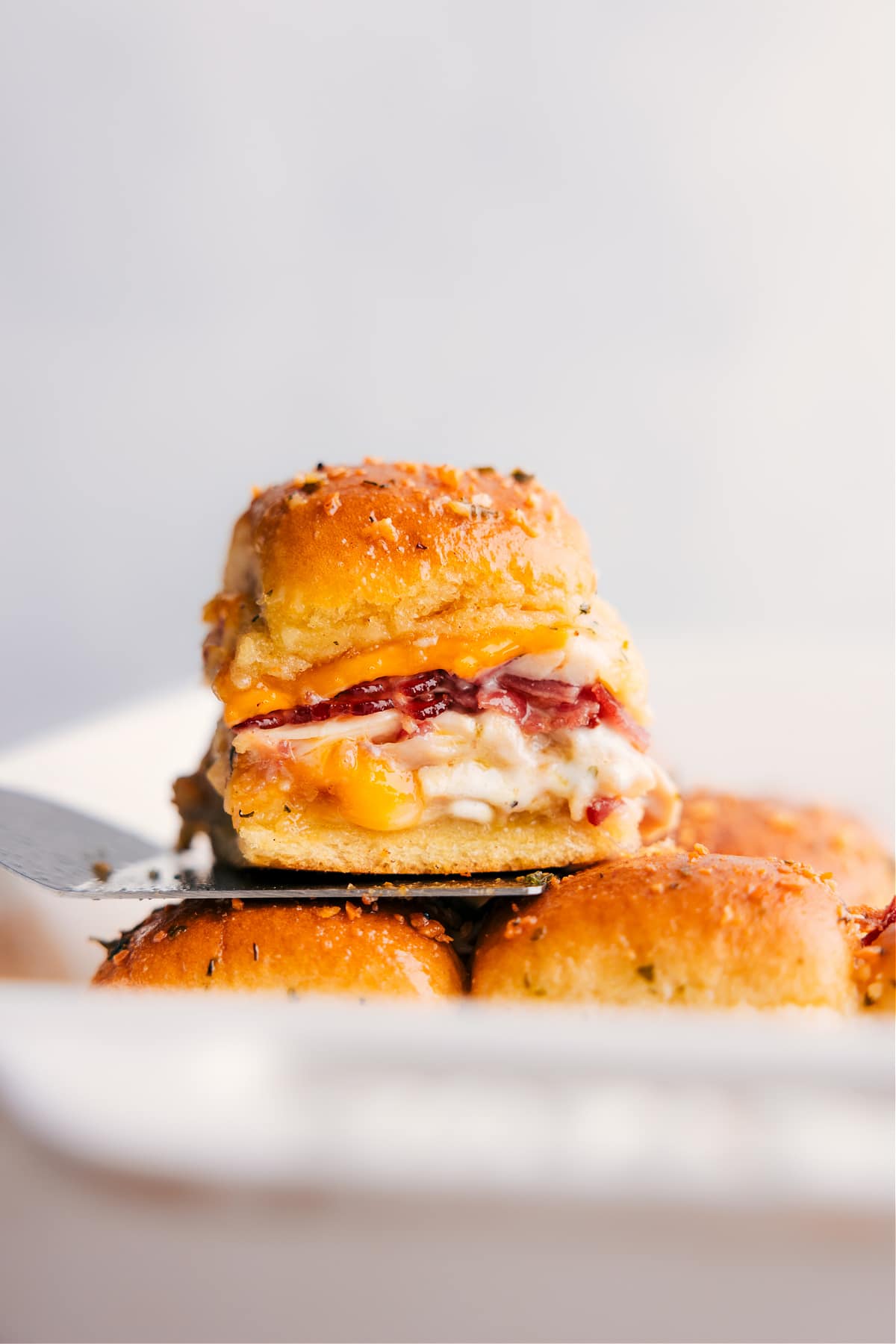 Stack of Chicken Bacon Ranch Sliders, with one sitting on a spatula.