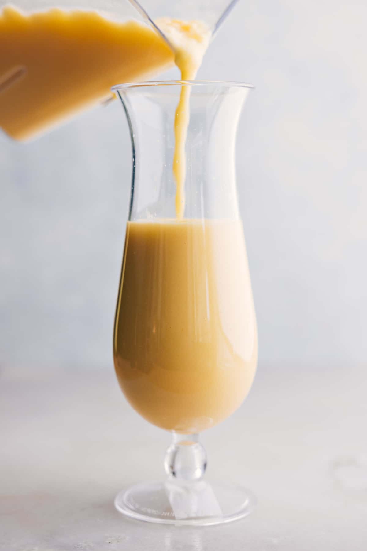 The pina colada being poured into a glass.