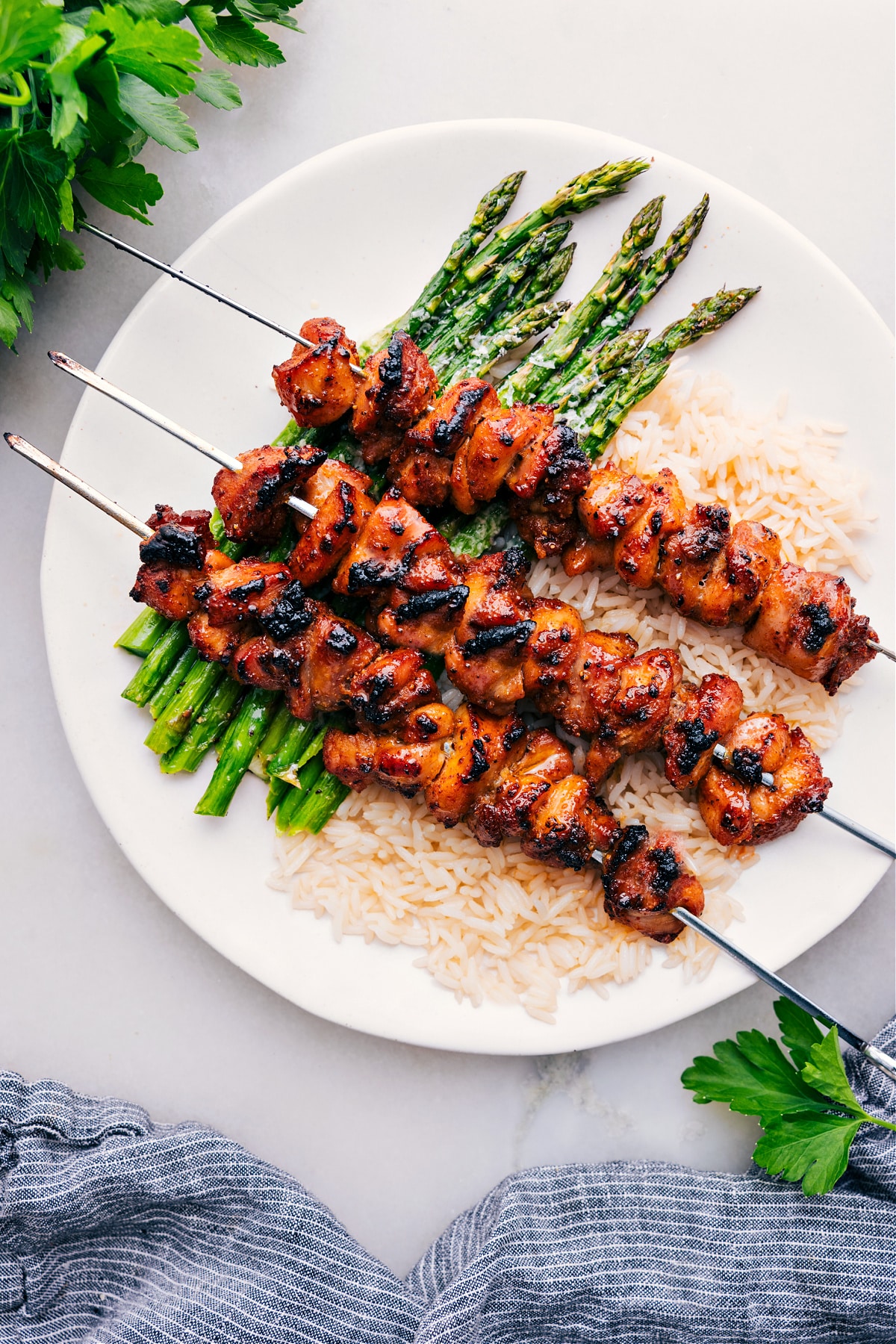 Baked Chicken Bites on skewers over rice and asparagus.