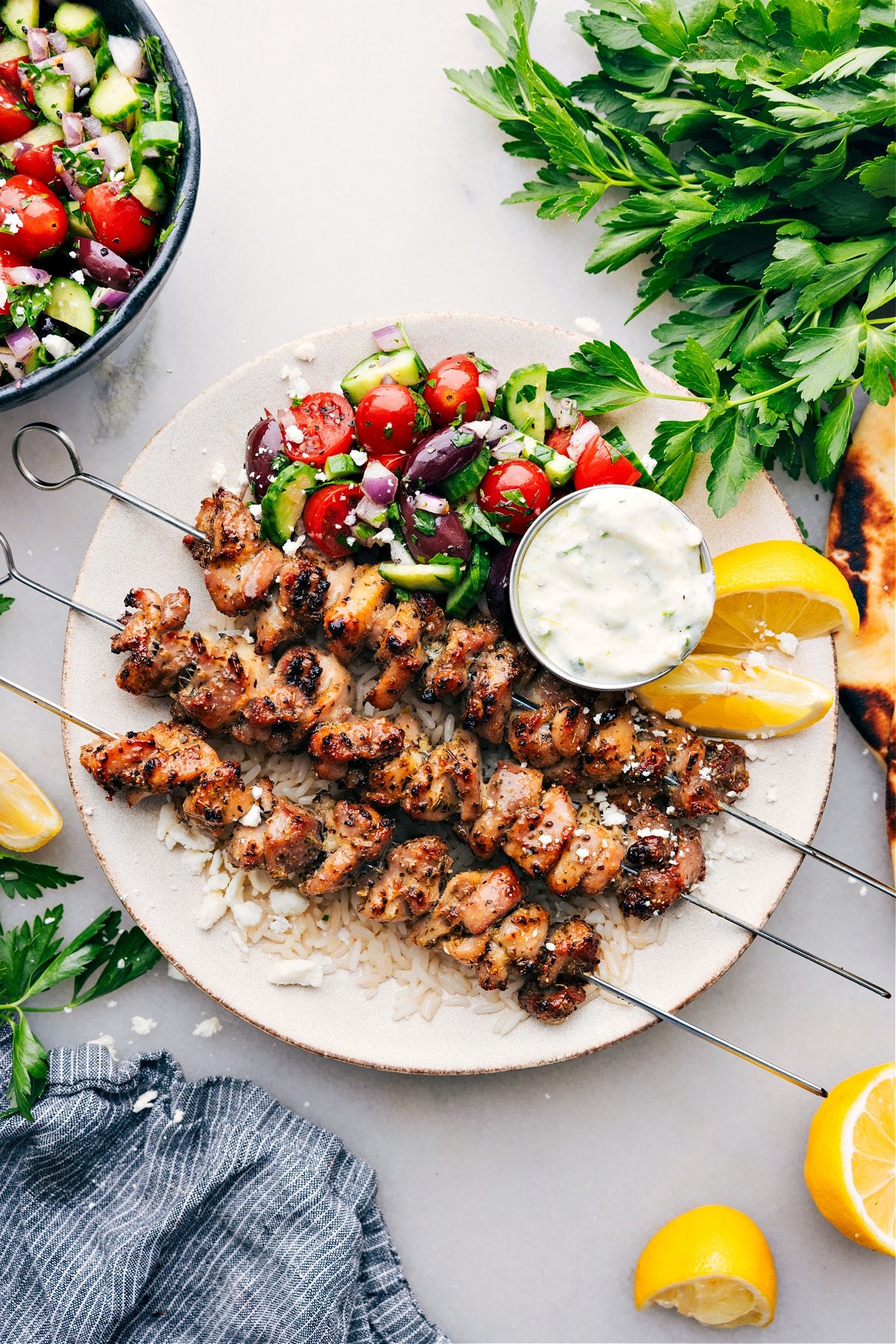 Greek Chicken Bowls on a plate with an easy greek salad, tzatziki dressing, all over rice.