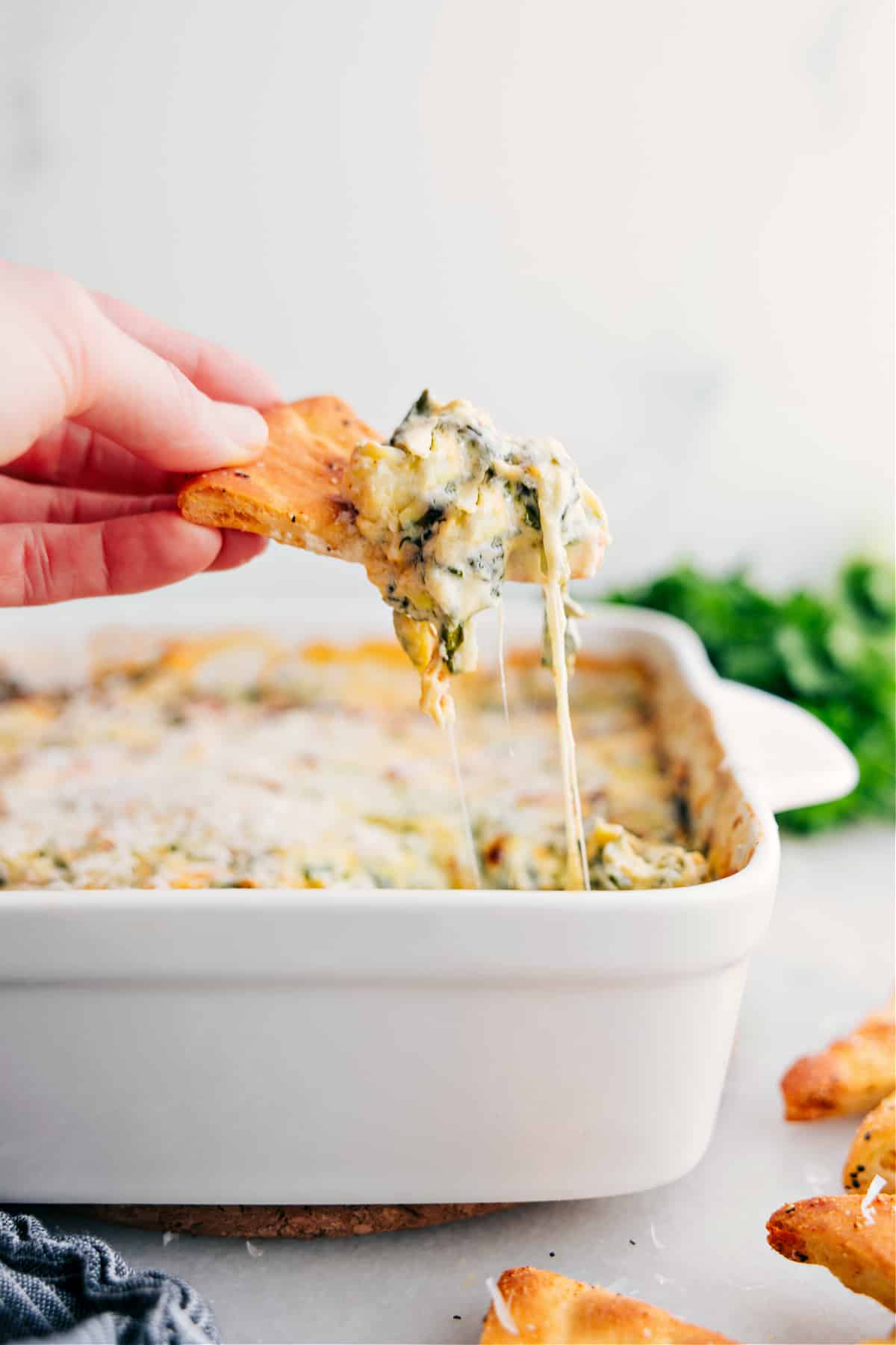 The Best Spinach Artichoke Dip Ever A big scoop of Spinach Artichoke Dip sits on a cracker.
