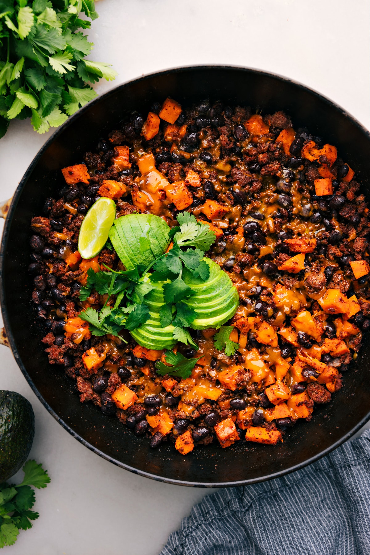 Hearty Ground Turkey Sweet Potato Skillet Ground Turkey Sweet Potato Skillet straight from the stove, topped with melty cheese, fresh avocado, and cilantro.