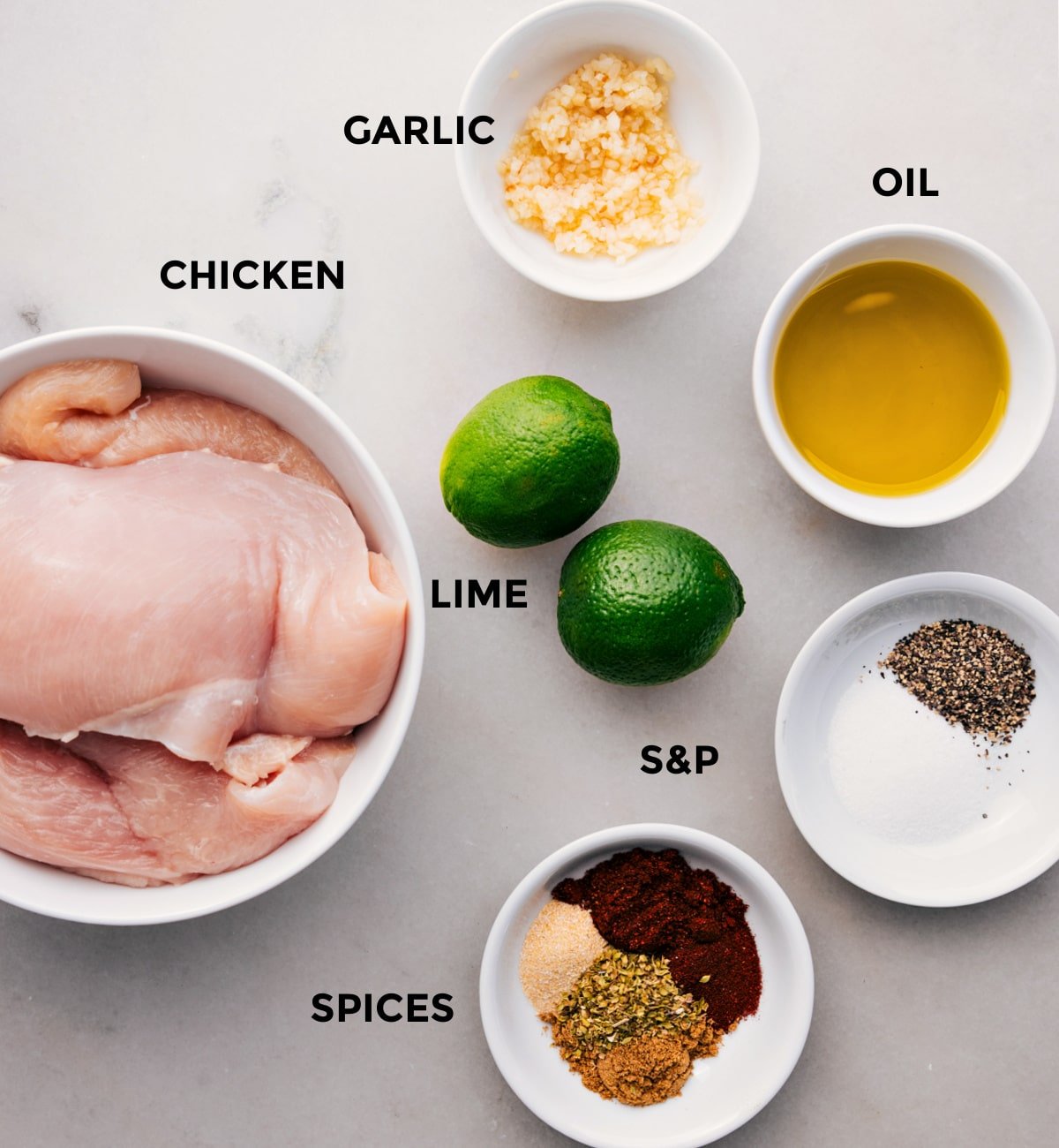 All the ingredients prepped for easy assembly, including oil, spices, lime, garlic, and chicken.