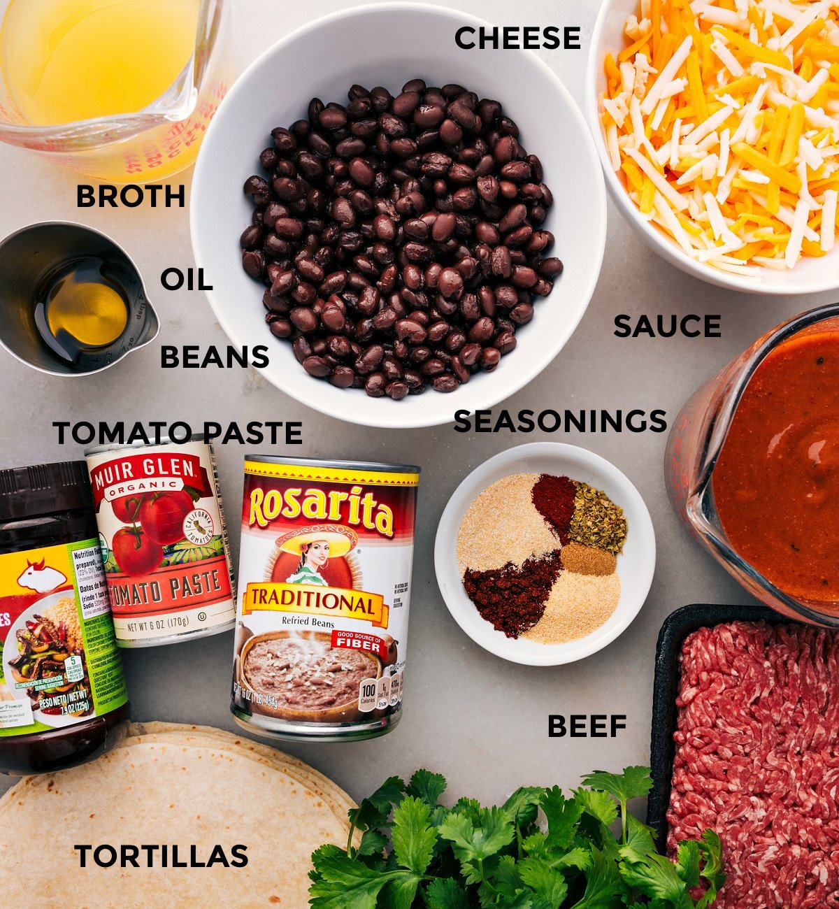 Ingredients prepped for easy assembly—broth, cheese, beans, sauce, seasonings, beef, tomato paste, and tortillas.